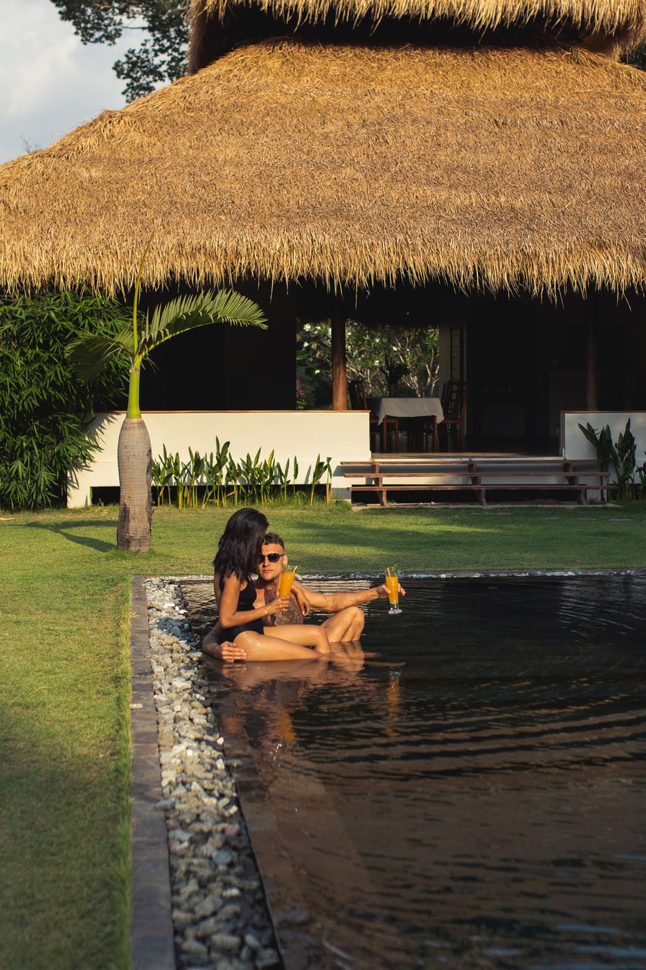 Guests relaxing in the pool at golden hour with drinks